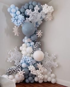 a balloon tree with snowflakes and balloons on the top is decorated in blue, white and silver