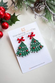 two christmas tree shaped earrings with bows on them