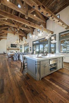 a large open concept kitchen with wood floors and beams on the ceiling, along with an island