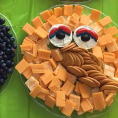 an assortment of cheeses and crackers are arranged in the shape of a face