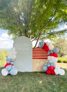 an american flag and balloon arch in the grass