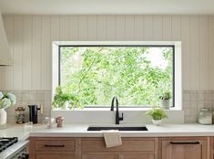 a kitchen with wooden cabinets and white counter tops, an open window above the sink