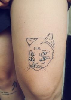 a woman's leg with a cat tattoo on the side of her thigh,