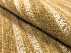 an up close shot of the fabric on a bed sheet that has been made with gold and white stripes