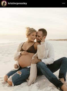 a pregnant woman sitting next to a man on the beach