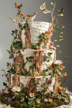 a three tiered wedding cake decorated with flowers and butterflies