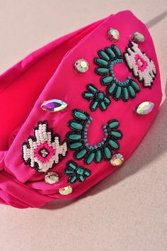 a bright pink purse with beaded flowers and jewels on the front, sitting on a table