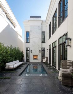 an outdoor swimming pool in the middle of a courtyard with chairs and tables around it