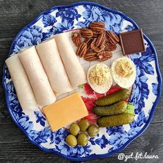 a blue and white plate topped with different types of food on top of a wooden table