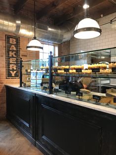 the interior of a bakery with many pastries on display behind glass counter tops and lights hanging from the ceiling