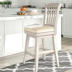 a wooden bar stool in a kitchen with white cabinets and gray rug on the floor