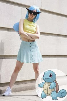 a woman with blue hair and glasses standing next to a building wearing a pokemon costume