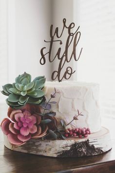 a wedding cake with succulents and the words we still do on it