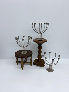 three wooden candlesticks with metal stems on each one and a round table in the middle