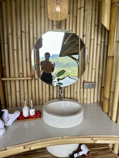 there is a mirror on the counter in this bamboo bathroom with towels and soaps