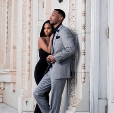 a man and woman standing next to each other in front of a white building with columns