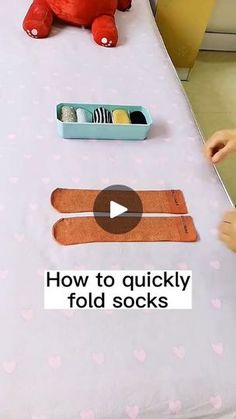 a child is playing with an odd object on a table that says how to quickly fold socks