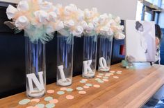 three vases with flowers are sitting on a table next to the letters n and k