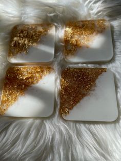 four white and gold coasters sitting on top of a fur covered floor with golden sprinkles