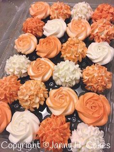 cupcakes with orange and white frosting are arranged in a plastic container on a table