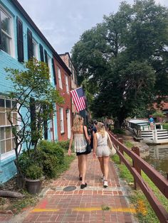 two young women walking down a brick path in front of a blue building with an american flag on it