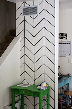 a green table sitting in front of a wall with black and white designs on it