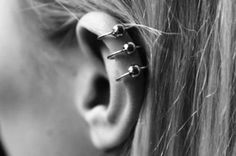 a woman's ear has three piercings on it and is shown in black and white