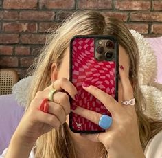 a woman taking a selfie with her cell phone in front of her face while sitting on a bed