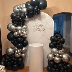 black and silver balloons are arranged in the shape of an arch