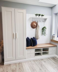 a room with white cupboards and shelves filled with hats, pillows and other items