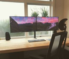 two computer monitors sitting on top of a wooden desk