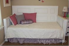 a white bed with red and purple pillows