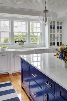 a large kitchen with blue cabinets and white counter tops, along with a striped rug on the floor