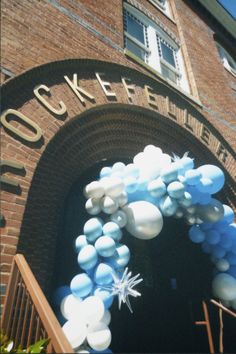 balloons are floating in the air at an entrance to a brick building with a clock on it