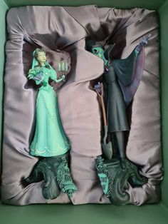 two figurines are in a box with satin material on the bottom and sides