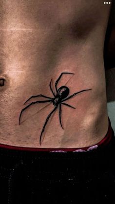 a black spider tattoo on the side of a man's rib - up stomach