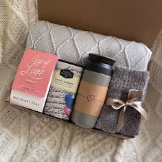 a coffee cup, tea bag, and some books in a box on a bed