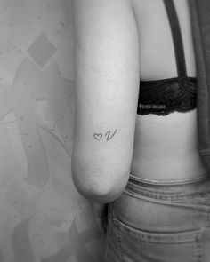 the back of a woman's left arm with a small heart tattoo on it