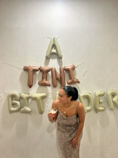 a woman is standing in front of balloons that spell out the word happy birthday,