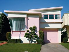 a pink and white house with trees in the front yard