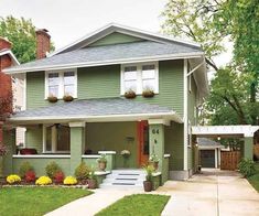 a green house with flowers in the front yard