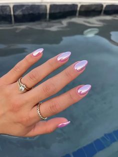 a woman's hand with pink and white manicures on it, next to a pool