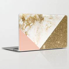 an open laptop computer sitting on top of a white surface with gold glitter and pink accents