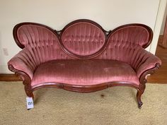 a pink couch sitting on top of a carpeted floor next to a white wall