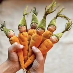 a hand holding a bunch of carrots with little people on them in the middle