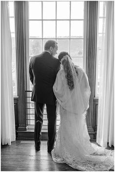 a bride and groom standing in front of a window