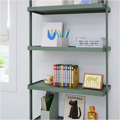 a green shelf with books and pictures on it in a room that has white walls