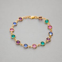 "Dainty, custom Mother's bracelet in gold with Swarovski Crystal birthstones. This sparkling birthstone bracelet would make a perfect gift for a mother or grandmother, with Swarovski crystals, set in gold, representing the birthstones of their family members. I can make this bracelet in a variety of ways for you. The photos above show some of the options: * a row of birthstones surrounded on either side by clear crystals * a repeated pattern of colors * a single color <>How to Order<&gt Gold Gemstone Bracelet For Birthday, Yellow Gold Round Crystal Bracelet Gift, Personalized May Birthstone Round Bracelet, Gold Bracelet For May Birthstone Gift, Gold Crystal Bracelet For May Birthstone Gift, Gold Crystal Birthstone Bracelet As Gift, Gold Bracelets For Anniversary With May Birthstone, Adjustable Bezel Set Bracelets As A Gift, Adjustable Bracelets With Bezel Setting As Gift