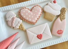 decorated cookies on a white plate with pink and red decorations in the shape of hearts