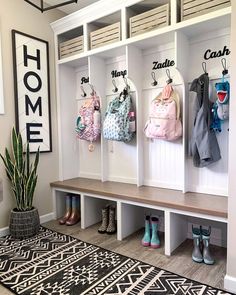 an entryway with white cubbys and coat racks filled with baby's clothes